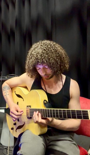Joseph leighton in riverbank playing guitar